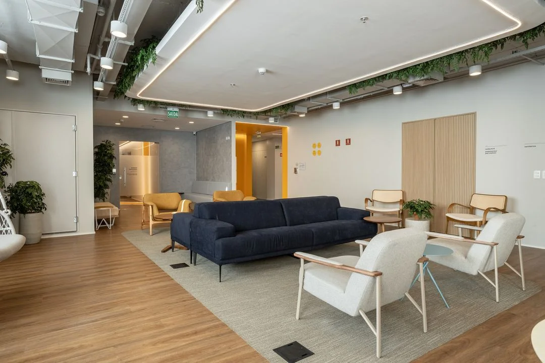 Sala de espera ampla do consultório. Na imagem, há dois sofás e seis poltronas sob um tapete.